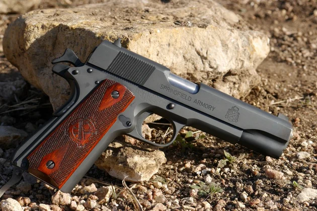 Pistolet Springfield Armory 1911 Mil-Spec en .45 ACP, posé au sol devant un rocher.
