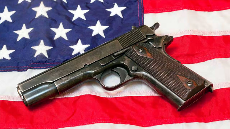Pistolet Colt 1911 posé sur un drapeau des États-Unis d’Amérique.