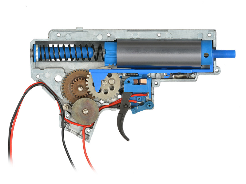 Vue interne d’une gearbox AEG avec engrenages, piston et ressort apparents.