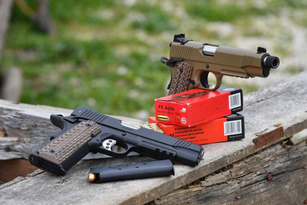 Deux pistolets Kimber 1911 modernes en .45 ACP avec chargeurs et munitions, sur fond de bois.
