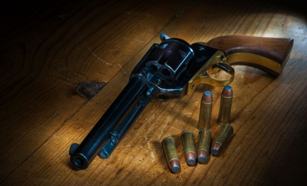Revolver Colt Single Action Army en .45 Colt posé sur une table en bois, avec six cartouches.