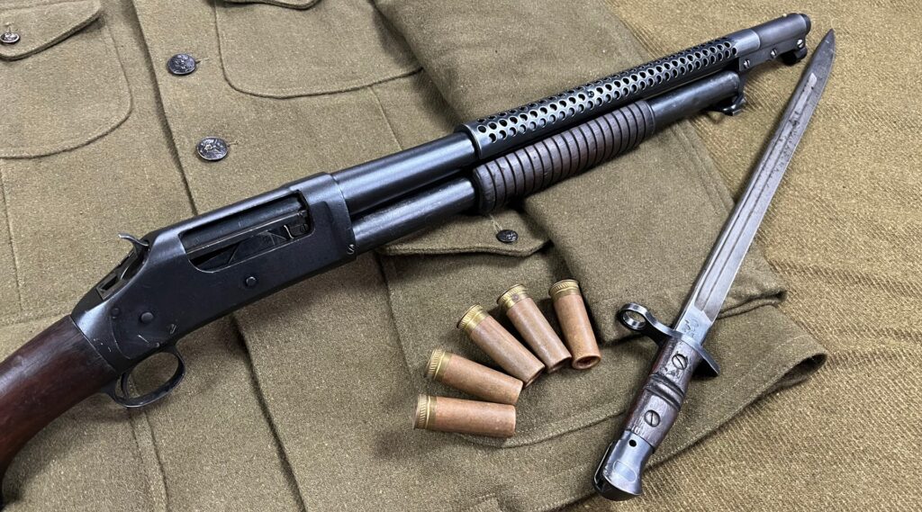 Fusil à pompe Winchester Model 1897 avec baïonnette et cartouches, posé sur un uniforme militaire.