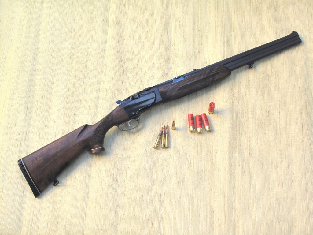 Fusil de chasse mixte superposé avec un canon lisse en bas et un canon rayé en haut, accompagné de cartouches et balles