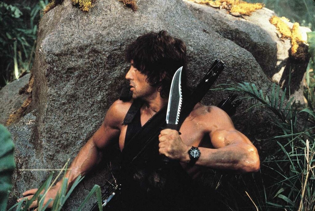 Sylvester Stallone en tenue militaire tenant un couteau Bowie modifié dans Rambo First Blood: Part II
