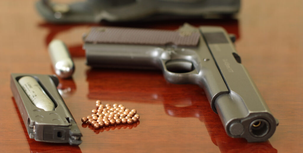 Pistolet CO₂ type 1911 calibre 4,5 mm avec chargeur, billes acier et cartouche CO₂ disposés sur une surface
