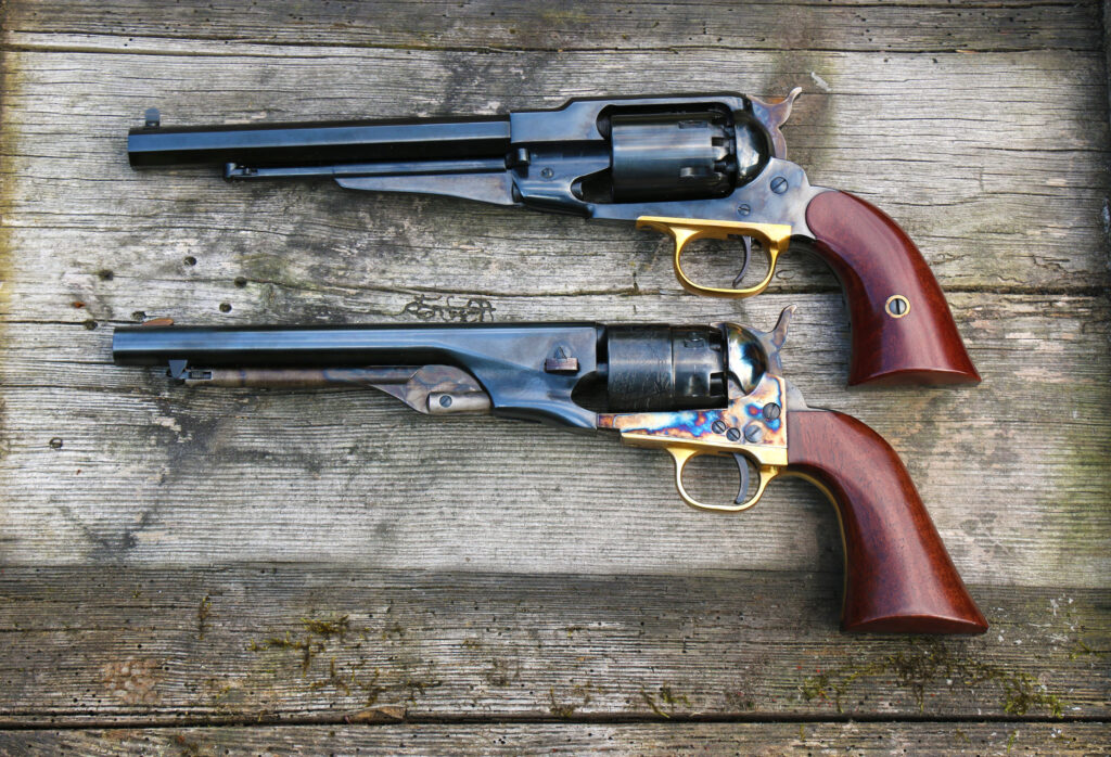 Comparaison de deux revolvers : Remington 1858 à carcasse fermée en haut et Colt 1858 à carcasse ouverte en bas, posés sur une planche en bois.