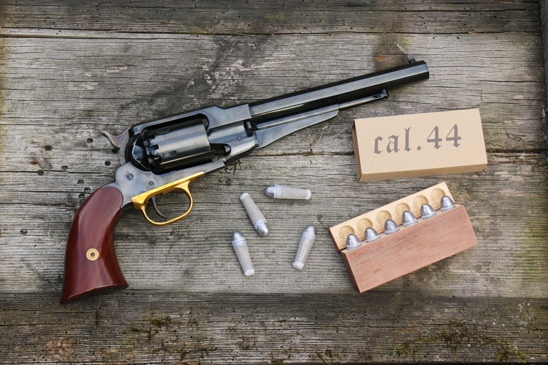 Revolver Remington New Model Army 1858 calibre .44 avec balles en plomb et boîte de rangement, posé sur une planche en bois ancien