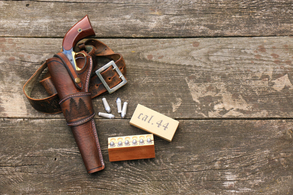 Holster en cuir marron pour revolver Remington 1858 avec ceinturon, accompagné de balles en plomb calibre .44 et d’une boîte de rangement.