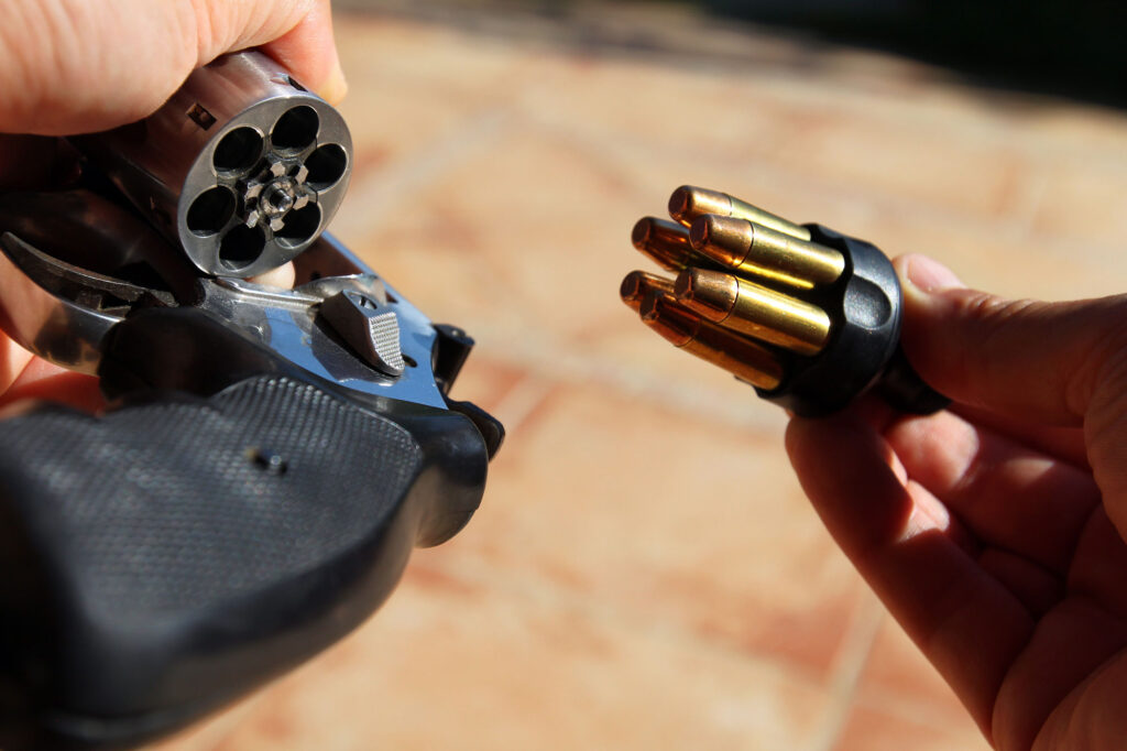 Rechargement d’un revolver avec un speedloader contenant plusieurs cartouches alignées.