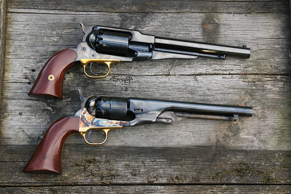 Comparaison entre un revolver Remington 1858 et un Colt 1851 Navy à poudre noire posés sur une planche en bois.