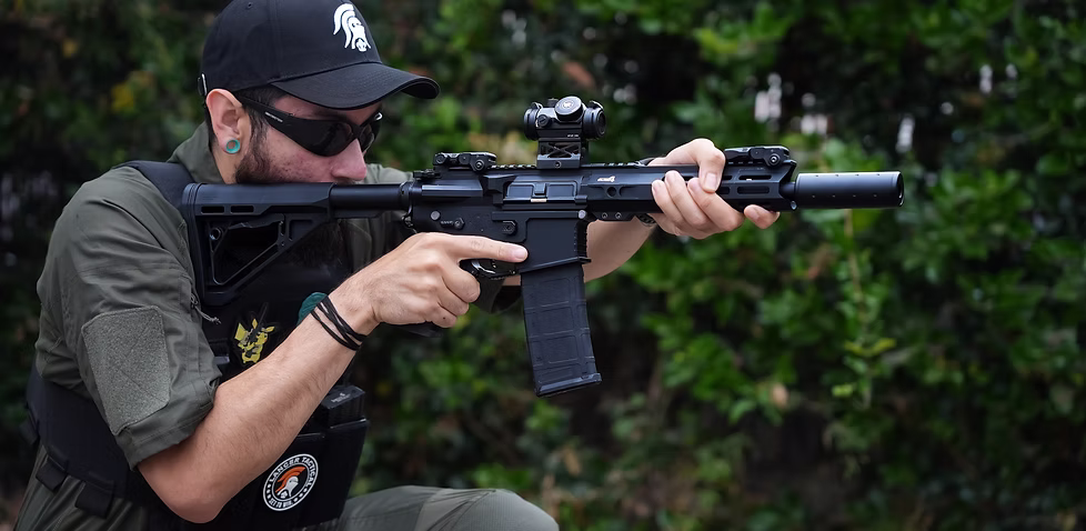 Lancer Tactical générations : joueur d’airsoft utilisant une réplique M4 moderne équipée d’un viseur point rouge et d’accessoires tactiques en extérieur.