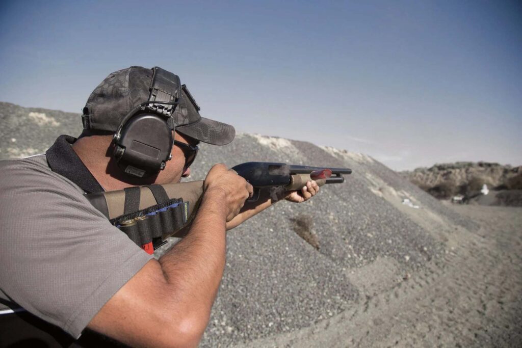 Tireur à l’entraînement avec un fusil à pompe Mossberg Maverick 88 sur un stand de tir extérieur